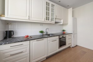 A modern kitchen with white cabinetry, a built-in oven, and a stainless steel sink. - Lumina 2room Apart with Balcony 6 guests (Warszawa)