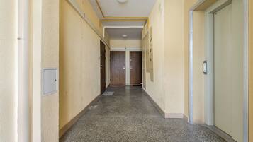 A hallway with lockers, a door at the end, and a light fixture on the ceiling.