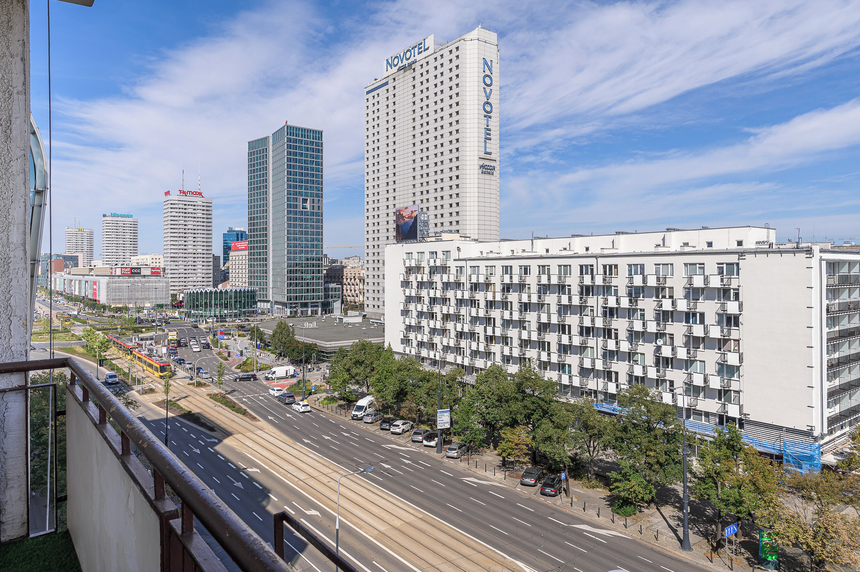 Een stadsgezicht met een opvallend hotel met een rastergevel, omringd door andere wolkenkrabbers en een drukke straat met voertuigen en voetgangers.