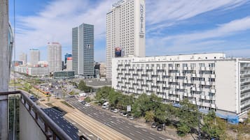 A cityscape with a prominent hotel featuring a grid-like facade, surrounded by other high-rise buildings and a busy street with vehicles and pedestrians.