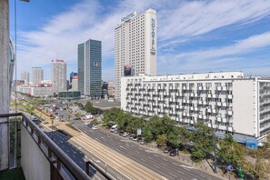 A cityscape with a prominent hotel featuring a grid-like facade, surrounded by other high-rise buildings and a busy street with vehicles and pedestrians. - Lumina 2room Apart with Balcony 6 guests (Warszawa)