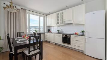 A modern kitchen with white cabinets, a Bosch oven, and a large window.