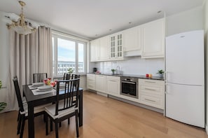 Een moderne keuken met witte kasten, een Bosch oven en een groot raam.