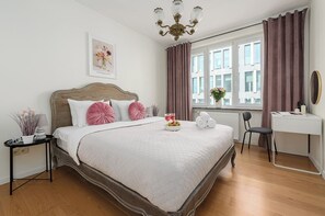 A neatly arranged bedroom with a bed, bedside table, and a desk with a chair. - Lumina 2room Apart with Balcony 6 guests (Warszawa)