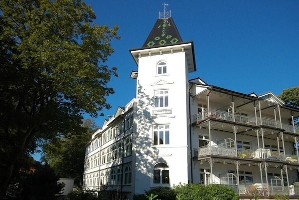 Monikerroksinen rakennus, jossa on huomiota herättävä torni, parvekkeita ja avoin taivas.