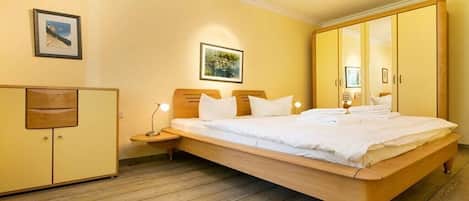 Un dormitorio con cama de madera, mesitas de noche, un armario y un cuadro enmarcado en la pared.