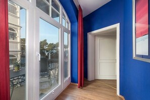 Ein Zimmer mit großem Fenster, einer Tür und Blick nach draußen.