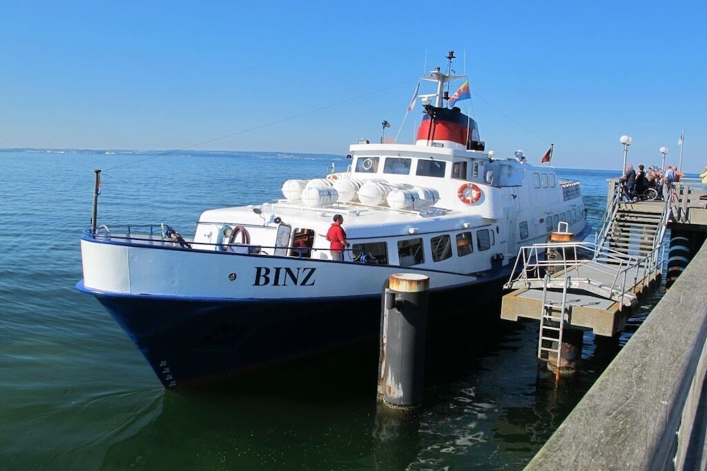 Un bateau nommé « BINZ » était amarré à un quai, d’où l’on avait une vue dégagée sur l’eau et sur un autre quai également amarré.