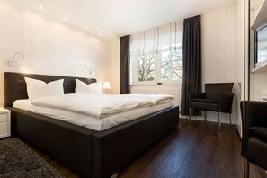 Moderni hotellihuone, jossa on suuri sänky, työpöytä ja tuoli.