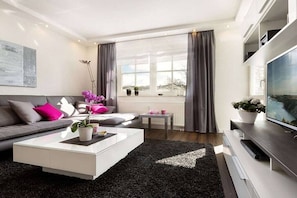A modern living room with a sofa, coffee table, and TV. - Sand dune in the Granitz house (Binz)