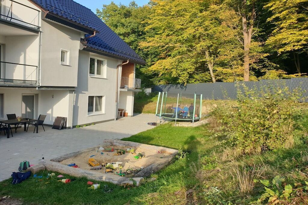 A residential building with a covered patio, outdoor seating, and a play area with toys.