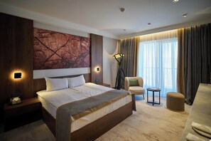 A modern hotel room with a large bed, a desk, a chair, and a floor lamp. - Lake Side Hotel (Qusar)