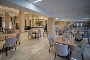 A spacious hotel lobby with multiple seating areas, a central bar, and a staircase. - Lake Side Hotel (Qusar)