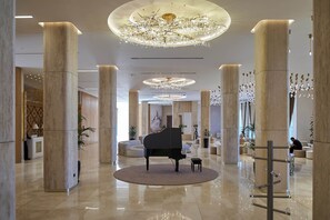 A grand lobby with a grand piano, high ceilings, and a large chandelier. - Lake Side Hotel (Qusar)