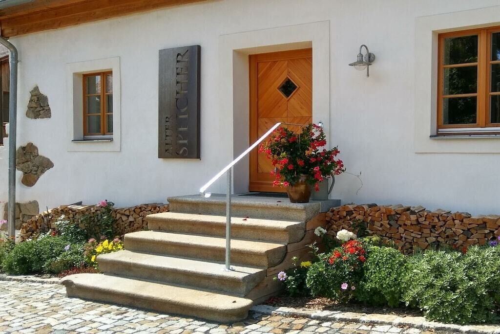 Un bâtiment avec une porte en bois, un escalier en pierre et une enseigne au-dessus de la porte.