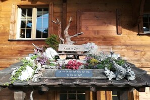 A wooden cabin with a rustic exterior, a wooden bench with a plaque, and a window with shutters. - Holiday apartment with 1 bedroom (Habkern)