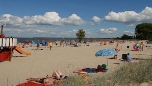 Uma praia com pessoas relaxando, tendas e um posto de salva-vidas.