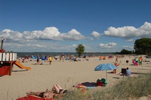 A beach with people relaxing, tents, and a lifeguard stand. - Holiday apartment with 1 bedroom (Ueckermünde)