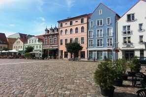 A cobblestone square with historic buildings, outdoor seating, and potted plants. - Holiday apartment with 1 bedroom (Ueckermünde)
