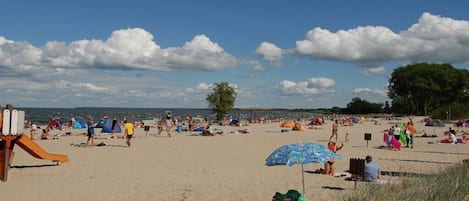 A beach with people sunbathing, tents, and a playground.