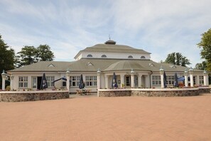 A large building with a central dome and multiple smaller domes, surrounded by a paved courtyard with outdoor seating and umbrellas. - Apartment in Ueckermünde with swimming pool (Ueckermünde)