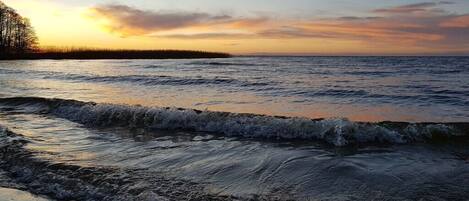 A coastal landscape with a body of water, waves, and a distant shoreline.