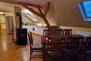 A dining area with a wooden table and chairs, a kitchen with a stove and cabinets, and a skylight. - Holiday apartment in Redwitz with sauna (Redwitz)
