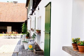 A courtyard with a table and chairs, potted plants, and a building with a green door. - Holiday apartment in Redwitz with sauna (Redwitz)