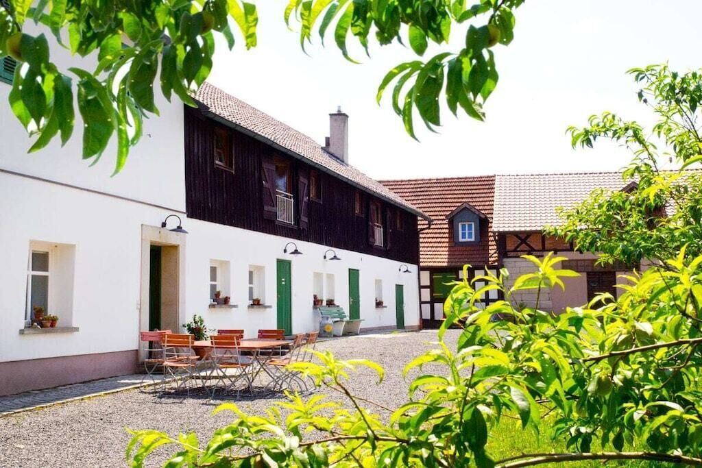 Ein Gebäude mit weißer Fassade und dunklem Holzboden, das einen Kieshof mit Außenmöbeln zeigt.