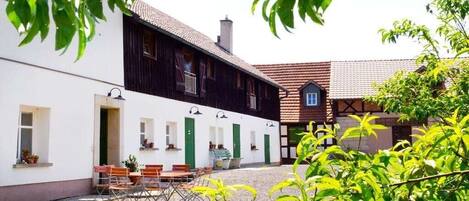 Ein Gebäude mit weißer Fassade und dunklem Holzboden, das einen Kieshof mit Außenmöbeln zeigt.