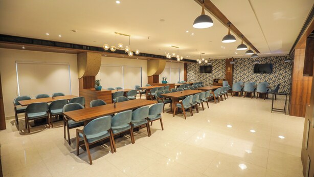 A conference room with multiple tables and chairs, a whiteboard, and a television on the wall.