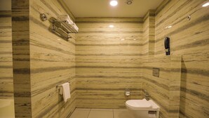 Une salle de bain avec un mur en marbre, des toilettes, un lavabo et un porte-serviettes.