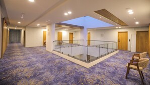 A hotel lobby with a central glass balustrade, patterned carpet, and multiple doors.