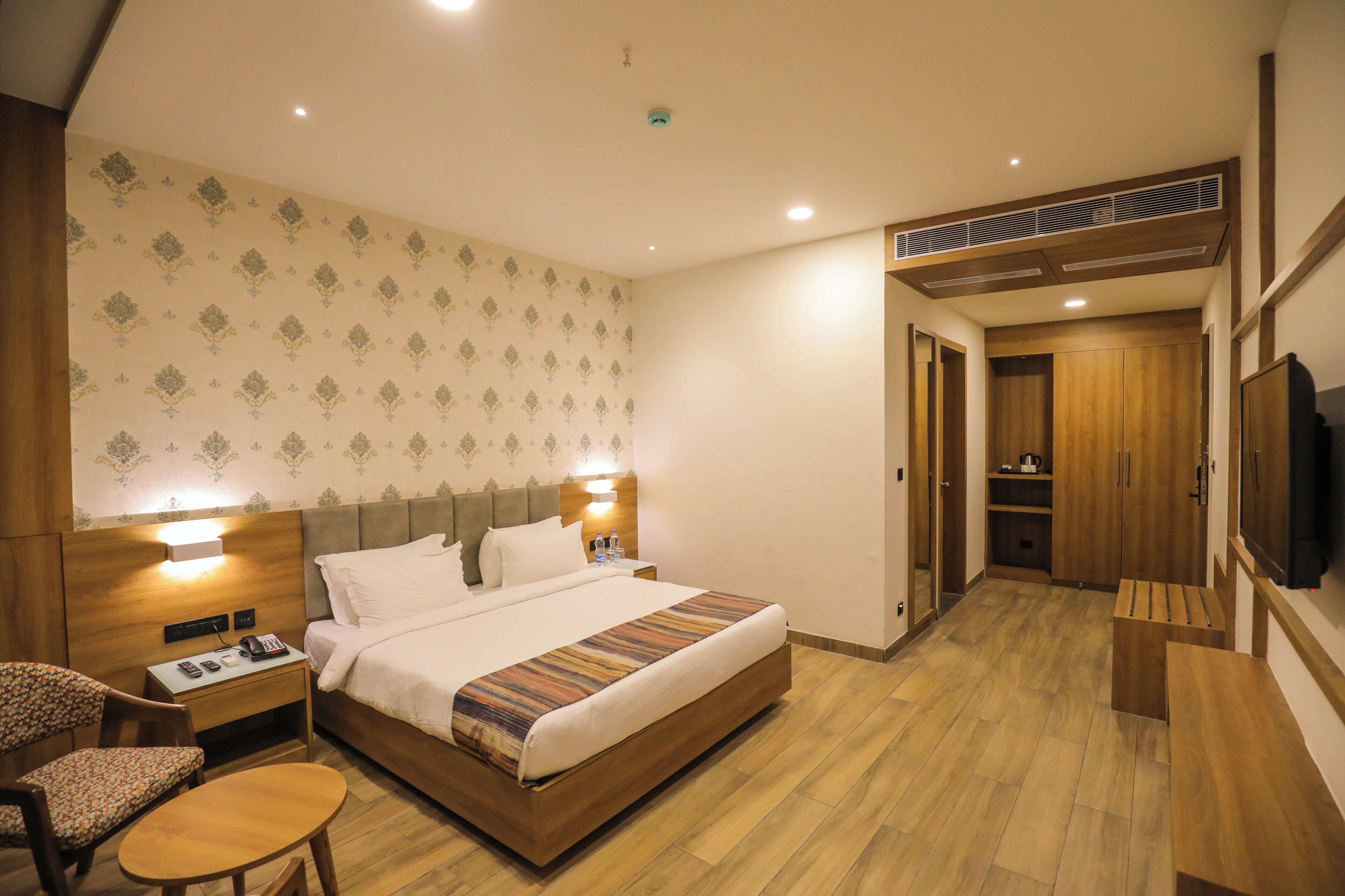Una habitación de hotel con cama, mesita de noche, silla y televisión.