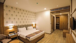 Une chambre d’hôtel comprenant un lit, une table de chevet, une chaise et un téléviseur.