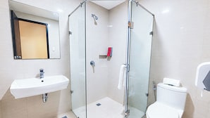 Un baño moderno con ducha de vidrio, lavabo blanco y un inodoro.