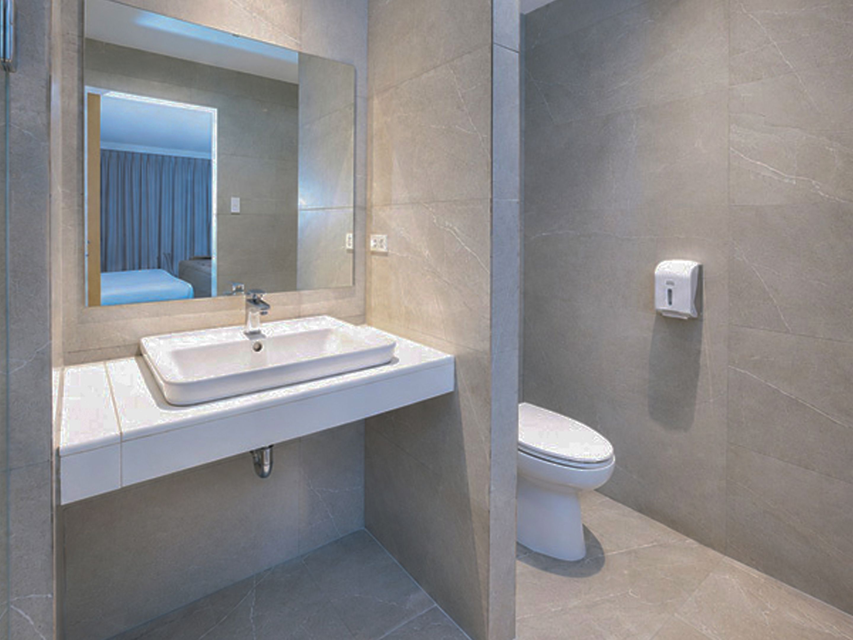 A modern bathroom with a rectangular sink, a mirror, and a toilet.