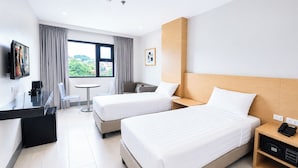 Habitación de hotel con dos camas, un escritorio con cafetera, televisor y vistas al exterior.