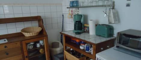 Cocina compacta con microondas, cafetera y un lavamanos pequeño.