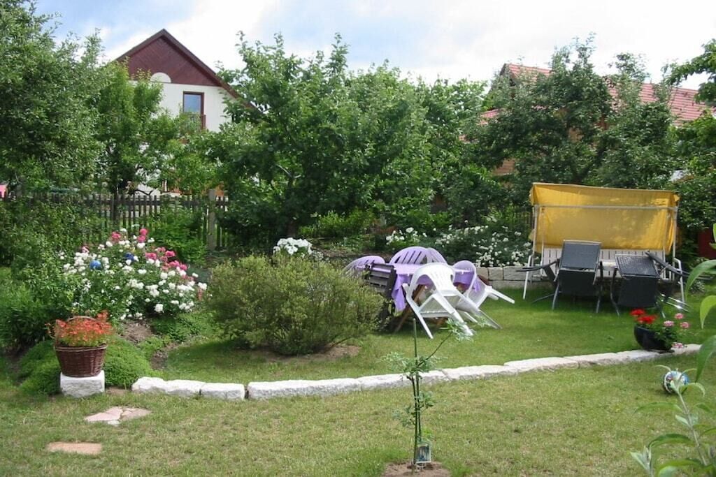 Un jardín con césped, un árbol pequeño y un toldo amarillo.