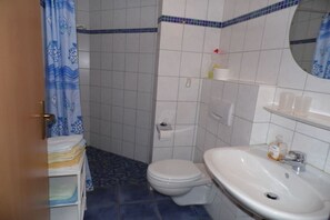 A bathroom with a toilet, sink, and a shower curtain with a fish pattern. - Holiday apartment with 1 bedroom (Elbinsel Krautsand)