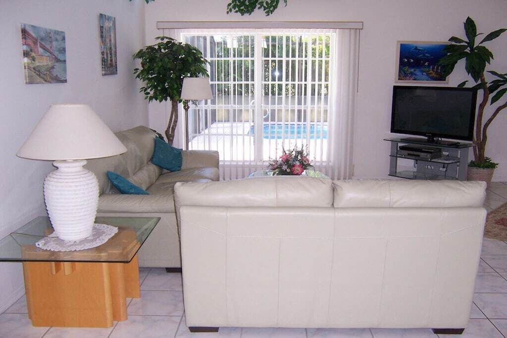 A living room with a sofa, a glass coffee table, a lamp, a television, and a plant.