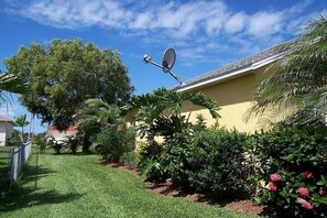 A residential property with a satellite dish, lush greenery, and a well-maintained lawn. - Villa in Cape Coral with swimming pool (Cape Coral)