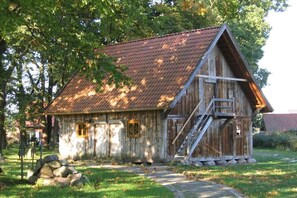 Ein rustikales Holzgebäude mit geneigtem Dach, einer Holztreppe und einem kleinen Fenster.