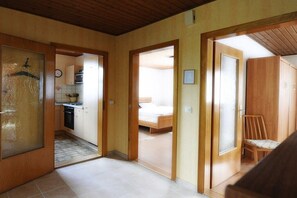 Ein Zimmer mit einem Bett, einer Holztür und einem Stuhl.