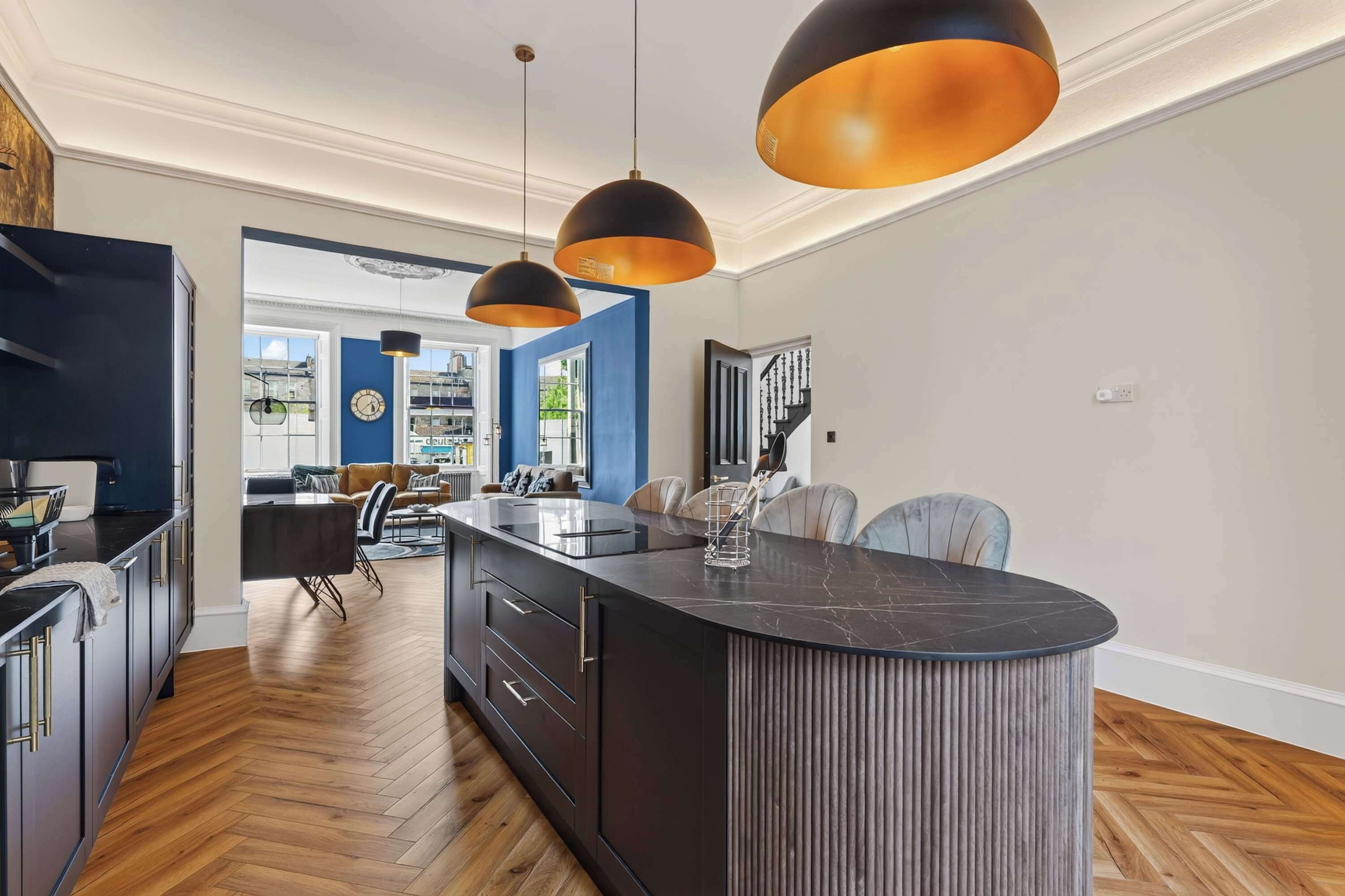 A modern kitchen with a central island, pendant lighting, and a view into the dining area.