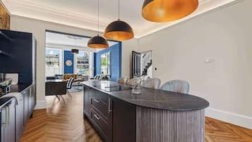 A modern kitchen with a central island, pendant lighting, and a view into the dining area.