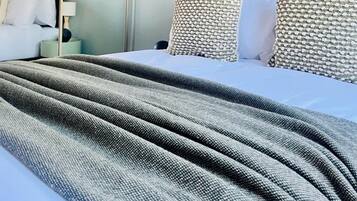 A neatly made bed with a grey textured blanket, a dark headboard, and two patterned pillows.