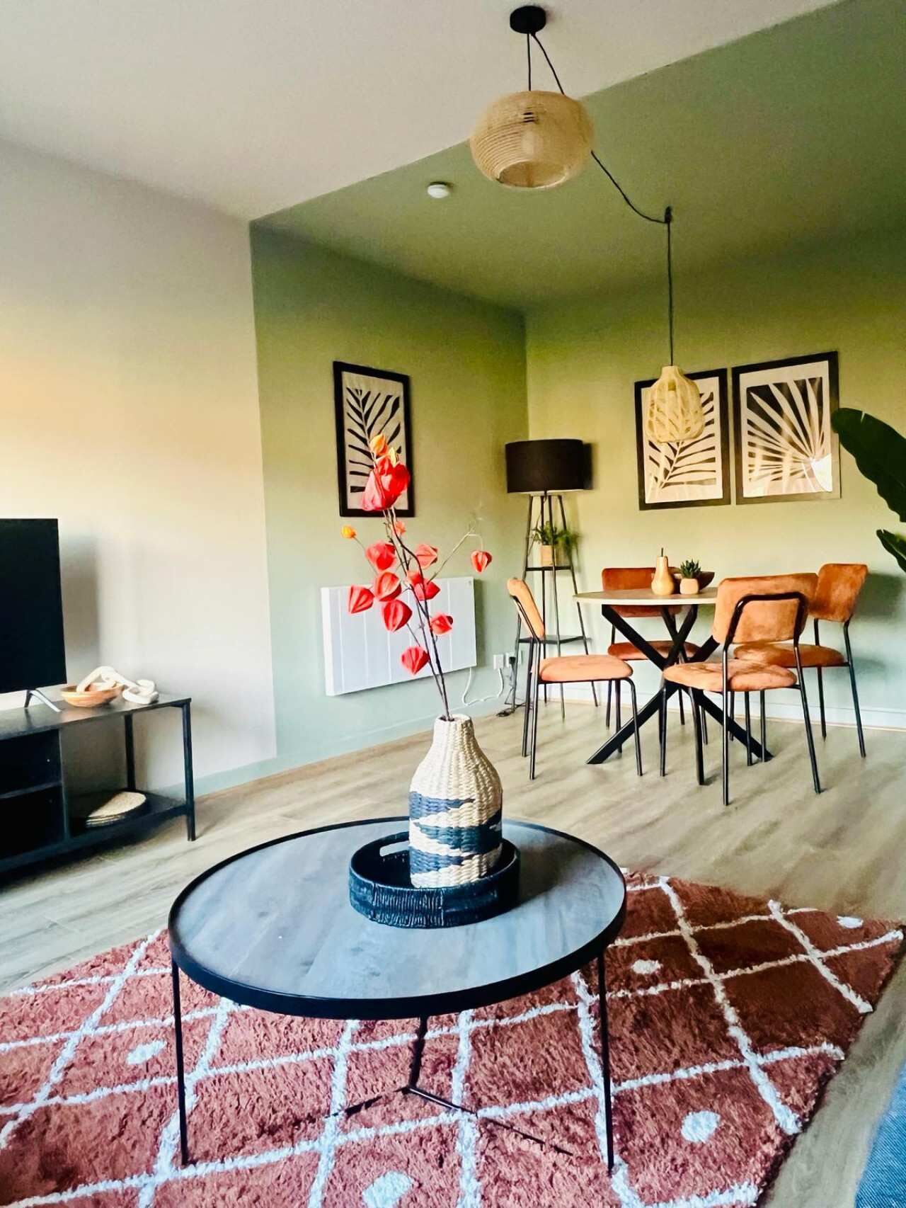 Una sala de estar moderna con una mesa de centro redonda, un comedor con mesa y sillas, y obras de arte en las paredes.
