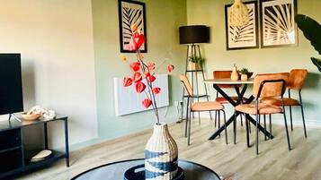 A modern living room with a round coffee table, a dining area with a table and chairs, and artwork on the walls.
